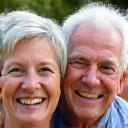 An older couple smiling warmly outdoors.