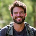 A man in his 30s with hiking gear, smiling.